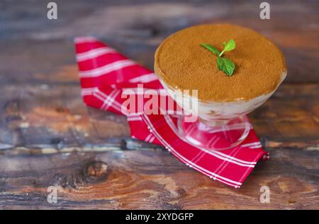 Il tiramisù torta in un bicchiere di vetro su sfondo di legno. Mascarpone Italiano deserto Foto Stock