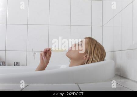 Donna bionda in una vasca da bagno con champagne Foto Stock