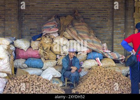 Lijiang, Cina, 30 settembre 2017: Venditore cinese di patate che vende pile e sacchi di patate in un mercato locale a Lijiang, Yunnan, Cina, Asia Foto Stock