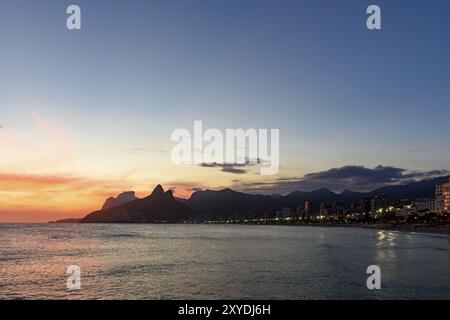 Paesaggio delle spiagge di Arpoador, Ipanema e Leblon a Rio de Janeiro durante il tramonto con le sue luci, la luna e il cielo e la collina due fratelli e GA Foto Stock