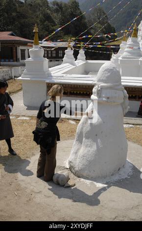 Un turista toccando un foro in una famosa pietra, Chorten Kora, Trashiyangtse, Est Bhutan Foto Stock