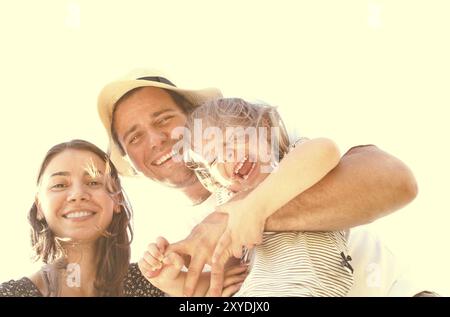 Felice giovane padre che porta la bambina mentre sorride la madre in piedi vicino durante il viaggio in famiglia in campagna durante il giorno estivo Foto Stock