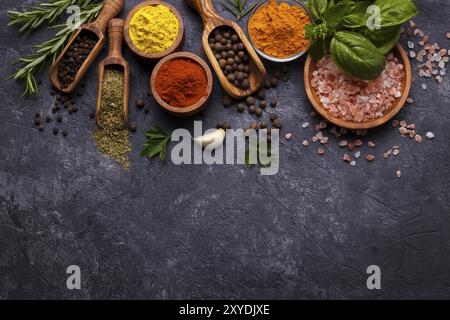 Spezie ed erbe su fondo di pietra nera. Vista dall'alto con spazio libero per menu o ricette Foto Stock