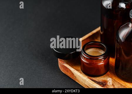 Raccolta di bottiglie in vetro ambrato disposte su un vassoio di legno su sfondo scuro Foto Stock