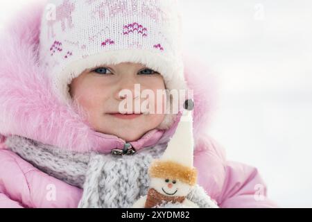 Bambino felice con pupazzo di neve nel parco invernale Foto Stock