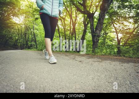 Primo piano di un piede di una ragazza sportiva in leggings e sneakers prima di fare jogging nella foresta. Il concetto di sport all'aperto Foto Stock