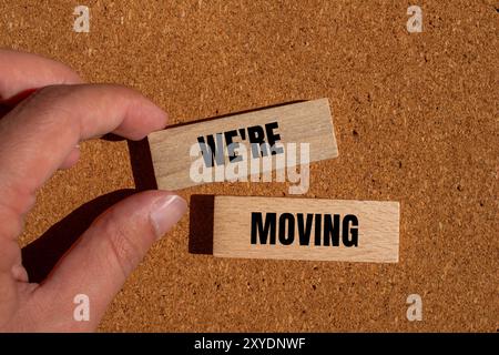 Stiamo spostando il messaggio scritto su blocchi di legno con sfondo marrone. Concettuale stiamo spostando il simbolo. Copia spazio. Foto Stock