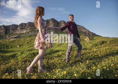 Giovane coppia sposata. Il tizio conduce una ragazza riccia con un mazzo di fiori. Il concetto di fiducia e famiglia giovane felice Foto Stock