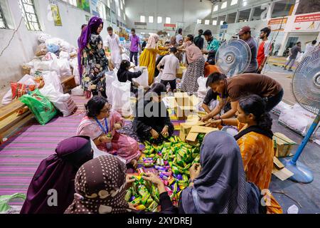 Gli studenti volontari che riforniscono, selezionano e confezionano materiali di sollievo nella palestra dell'Università di Dhaka, da inviare alle vittime delle inondazioni acros Foto Stock