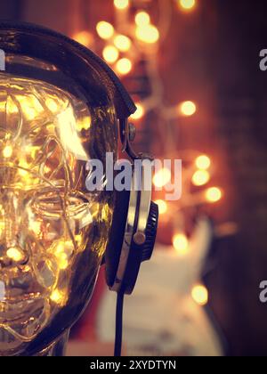 Cuffie su una testata in vetro con luci di Natale, Natale in musica, la chitarra rock con luci in background Foto Stock