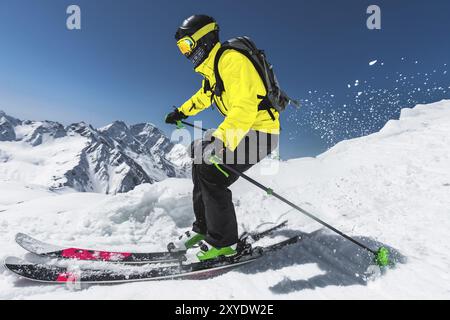 Sciatore professionista alla velocità prima di saltare dal ghiacciaio in inverno contro il cielo blu e le montagne Foto Stock