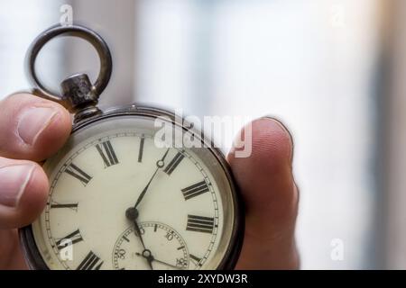 Il tempo passa vicino: L'uomo sta tenendo un orologio d'annata nella sua mano, contesto di affari, spazio di copia Foto Stock