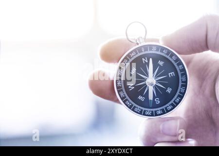 Primo piano di un mans mano che tiene una bussola nella sua mano. Concetto per il business, per l'innovazione Foto Stock