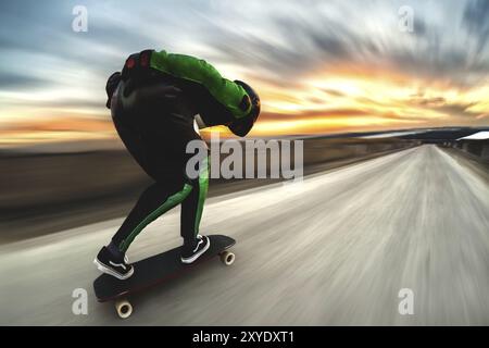 Un uomo con casco e tuta in pelle, in una speciale cremagliera ad alta velocità, cavalca su una lunga longboard per scendere in discesa a galla sullo sfondo di un beauti Foto Stock
