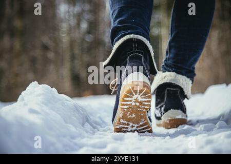 Ragazza in jeans blu è trekking in inverno, gambe e scarpe Foto Stock