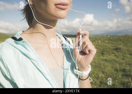 Primo piano della faccia inferiore di una giovane runner in natura prima di fare jogging. Chin e labbra sorridenti della sportiva e mano sul microfono di Foto Stock