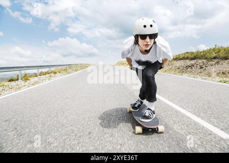 Un giovane con casco e occhiali da sole percorre una strada di campagna ad alta velocità sotto la pioggia tra le nuvole del temporale Foto Stock