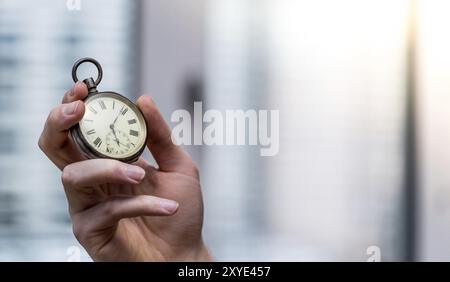 Il tempo passa vicino: L'uomo sta tenendo un orologio d'annata nella sua mano, contesto di affari, spazio di copia Foto Stock