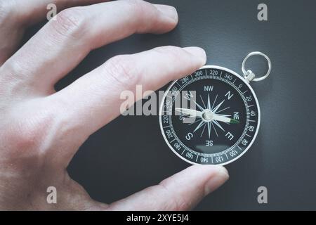 Primo piano di un mans mano che tiene una bussola nella sua mano. Concetto per il business, per l'innovazione Foto Stock