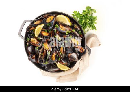 Cozze alla marinara, moules mariniere, top shot in un recipiente di cottura con prezzemolo fresco su un fondo bianco con un posto per il testo Foto Stock