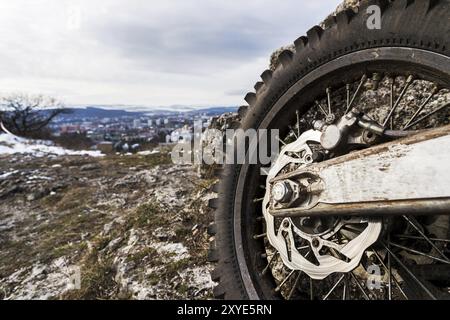 Ruota con razze e disco freno più catena motociclistica Enduro. Primo piano sullo sfondo di un paesaggio Foto Stock
