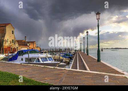 Vista nuvolosa del porto dell'isola di Burano, del porticciolo, del famoso monumento di Venezia, della regione del Veneto, dell'Italia, Europa Foto Stock