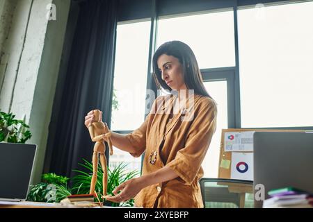 Una giovane donna con lunghi capelli bruna è in piedi in un ufficio, a regolare una statuetta di legno. Foto Stock