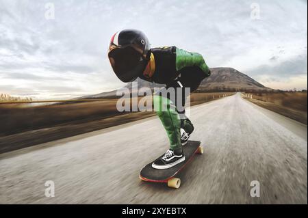 Un giovane con casco integrale e una tuta in pelle in uno speciale rack, cavalca un longboard sul tramonto afsaltu sulle montagne sullo sfondo e sul bellissimo sk Foto Stock