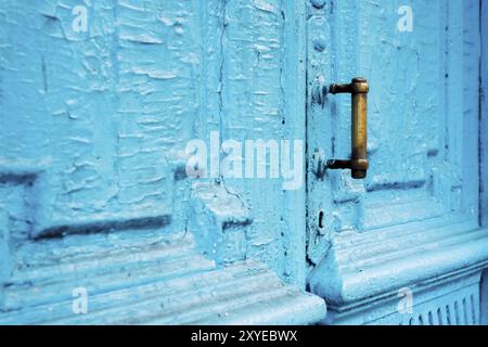 Primi piani con buchi di serratura con tende e una maniglia sul blu molte volte dipinto porta vintage in legno a doppia canna incrinata del secolo scorso con una pos Foto Stock