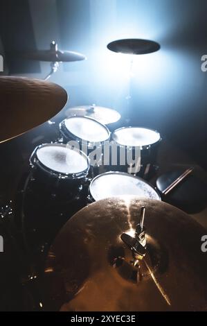 Primo piano tamburo in una stanza buia contro lo sfondo del riflettore. Sfondo atmosferico simbolo della musica rock o jazz. Piastre in rame su Foto Stock