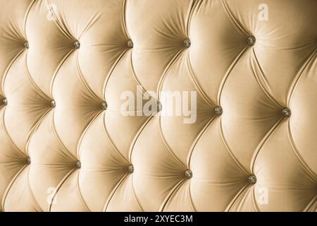 Fondo in morbido tessuto beige con bottoni simmetrici sugli angoli dei diamanti. Elementi mobili morbidi e costosi. Sfondo di lusso Foto Stock