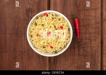 Una foto aerea di una ciotola di tagliolini con un peperoncino rosso e un posto per il testo, al buio su un rustico texture di sfondo Foto Stock