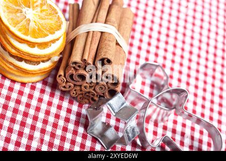 Arancia, cannella, anice e taglierina per biscotti su un panno a scacchi Foto Stock