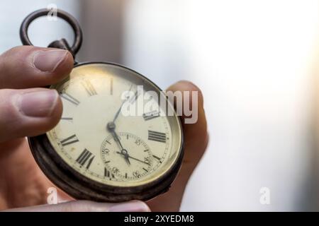 Il tempo passa vicino: L'uomo sta tenendo un orologio d'annata nella sua mano, contesto di affari, spazio di copia Foto Stock