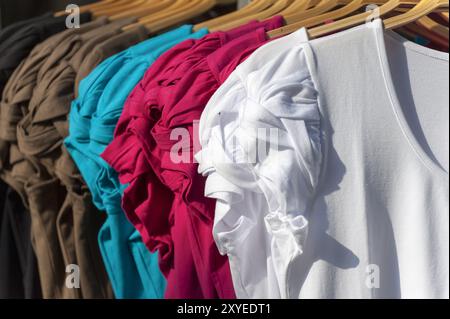 Camicette di colori diversi su grucce Foto Stock