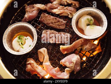 Primo piano della carni bovine e capesante essendo cotta sul fuoco a un giapponese ristorante grill Foto Stock