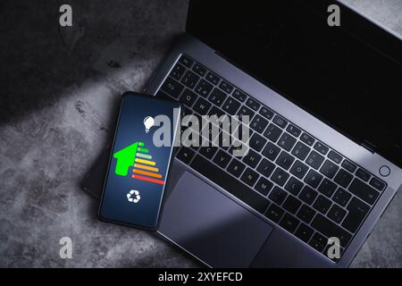 Smartphone che visualizza sullo schermo la valutazione di efficienza della casa. Valutazione dell'efficienza della casa sullo schermo del telefono. Concetto di casa ecologica e bioenergetica. Classe energetica. Foto Stock