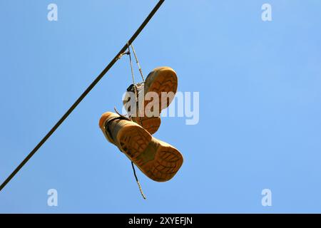 Scarpe appese a una linea aerea a un'altezza elevata Foto Stock