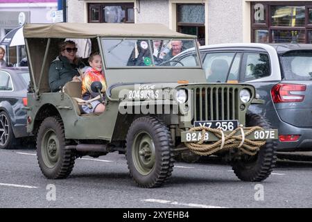 Jeep verde mimetica dell'esercito degli Stati Uniti, vintage, era ww2, 82AB 307E, che partecipa a una corsa di trattori attraverso il centro della città. Ballycastle, Regno Unito - 24 agosto 2024. Foto Stock