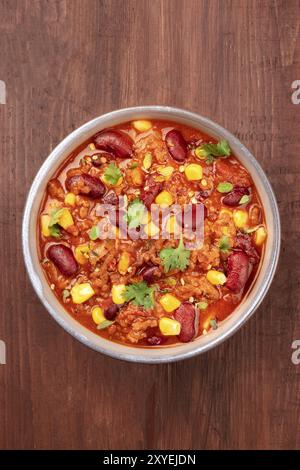 Chili con carne, tradizionale piatto messicano, girato dalla parte superiore al buio su un rustico sfondo di legno con un posto per il testo Foto Stock