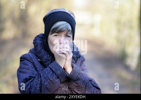 Ritratto di una donna che si scalda le mani Foto Stock