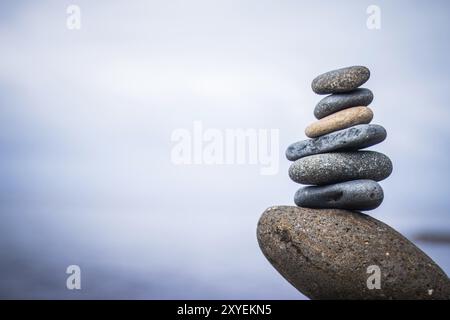 Vicino la foto di una pietra cairn all'esterno. Il mare in sfondo sfocato Foto Stock