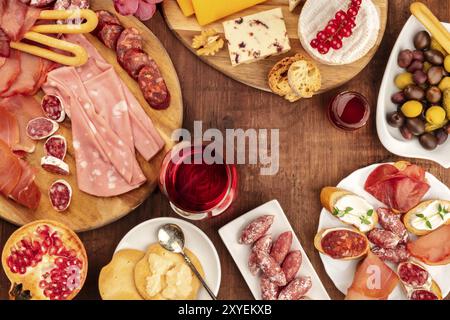 Degustazione di salumi. Una foto di molte diverse salsicce e prosciutti, salumi e un vassoio di formaggi, girato dalla parte superiore su un sfondo rustico con una gla Foto Stock