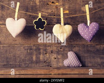 Tessuto di tre forme di cuore con un piccolo a forma di fiore chalkboard su una parete in legno, il giorno di San Valentino o la festa della mamma concept Foto Stock