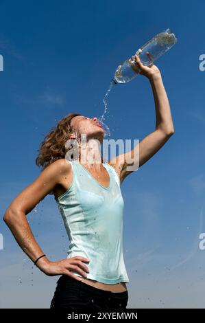 Una giovane donna le punta il contenuto di una bottiglia d'acqua in faccia Foto Stock