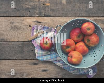 Deliziose mele biologiche in un vecchio usato scolapasta su una tavola in legno rustico, tono di piatti in stile vintage con vista da sopra Foto Stock