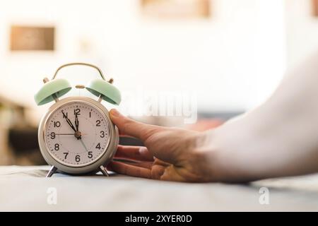 L'uomo sta spingendo una sveglia, il sole al mattino, sfondo sfocato Foto Stock