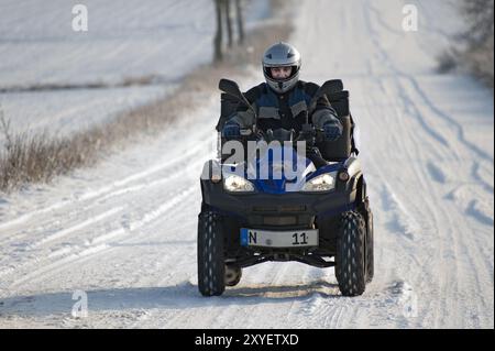 Guida attiva senior su un quad in inverno Foto Stock