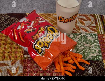 Cheetos croccante con un bicchiere di latte. Charles Elmer Doolin inventò Cheetos nel 1948, Frito-Lay è una filiale della PepsiCo. Chester Cheetah-Mascot! Foto Stock