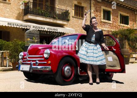Giovane donna con auto d'epoca di fronte a una pizzeria Foto Stock